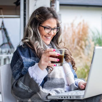 A young woman is drinking coffee in the garden of her house
