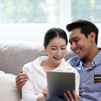 Portrait of Young Asian Couple relaxing in living room using tablet shopping online simple lifestyle in modern family