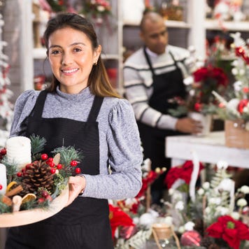 Two shop owners create festive decorations for their store.