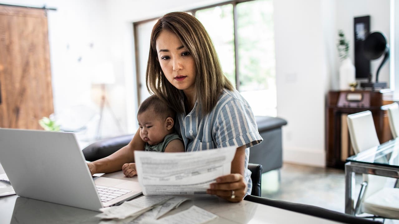 woman doing paperwork at kitchen table with baby in lap