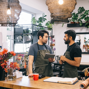 Two flower shop owners are seen actively engaged in inventory management, maintaining a well-organized and beautiful workspace.
