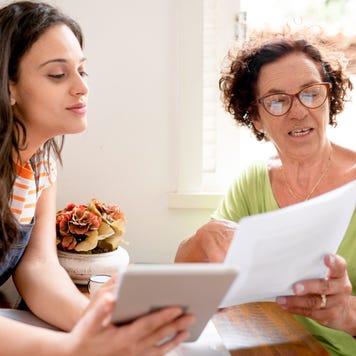 Woman helping her mom with home finances using a digital tablet