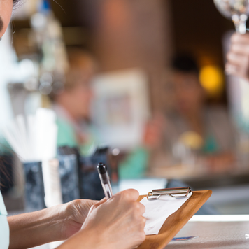 Woman signing receipt after paying bar tab in restaurant