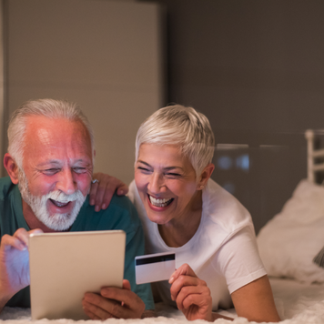 Happy senior couple using credit card and digital tablet