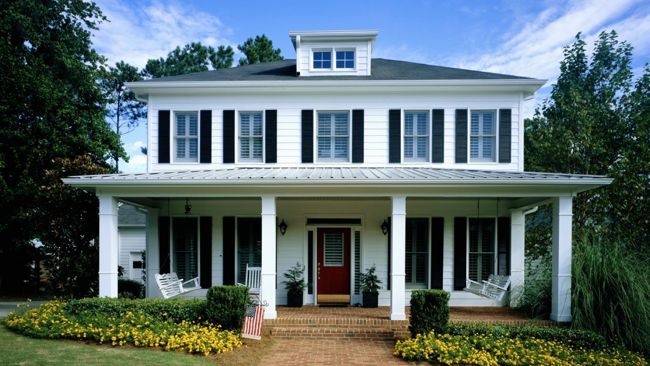 White wooden house, flowers blooming around front porch