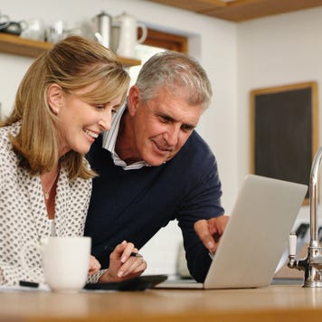 A senior couple planning their finance and paying bills while using a laptop at home.