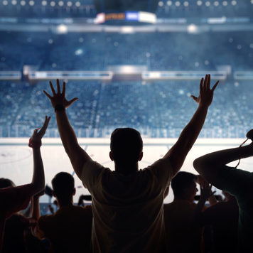 Hockey fans celebrating at a hockey game. We see their silhouettes and fans attributes