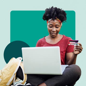 Student sitting down on her laptop while holding a credit card in one hand