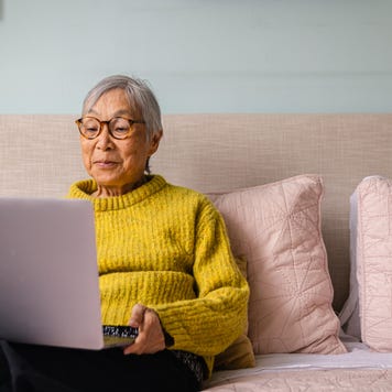 woman using laptop while sitting in bedroom