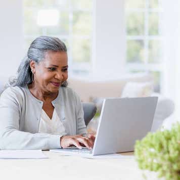 Older woman sits at her computer answering emails.