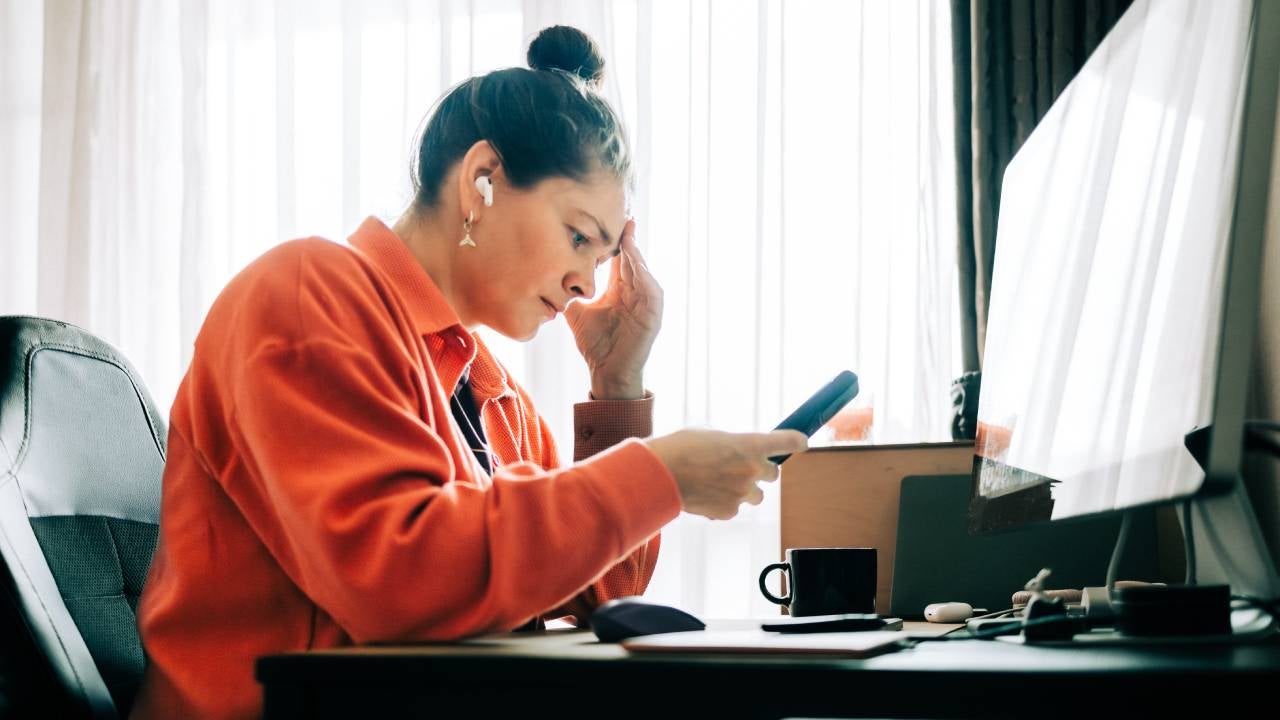 A distressed woman looks down at her phone.