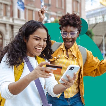 design image of two woman smiling and one is holding a credit card and phone in her hand