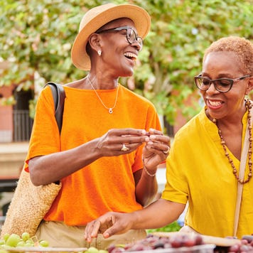 Two women shopping together at an outdoor food market