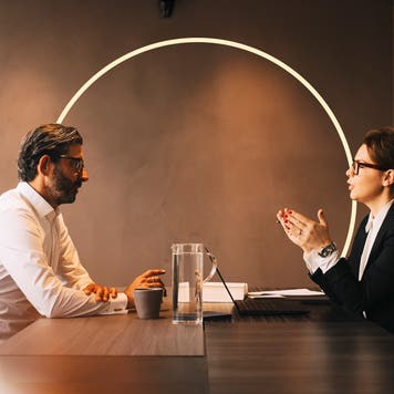 Two people having a discussion at a conference room table.
