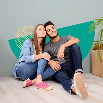 Couple sitting together with boxes stacked around them