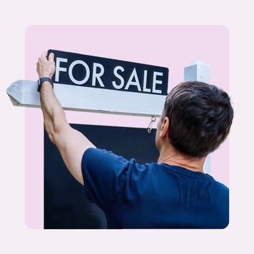 A person putting up a "For sale" sign