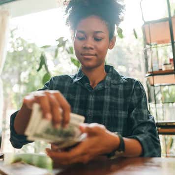 A young woman counts dollar bills