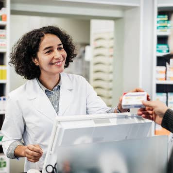 female pharmacist wearing white lab coat interacting with customer
