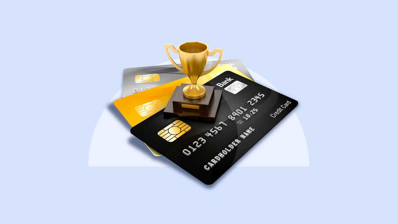 A tiny golden cup trophy standing on three fanned out credit cards.