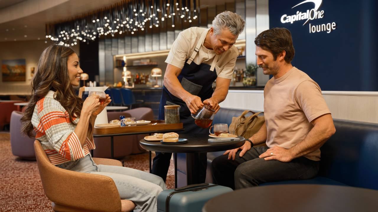 2 people sitting in a Capital One lounge drinking coffee