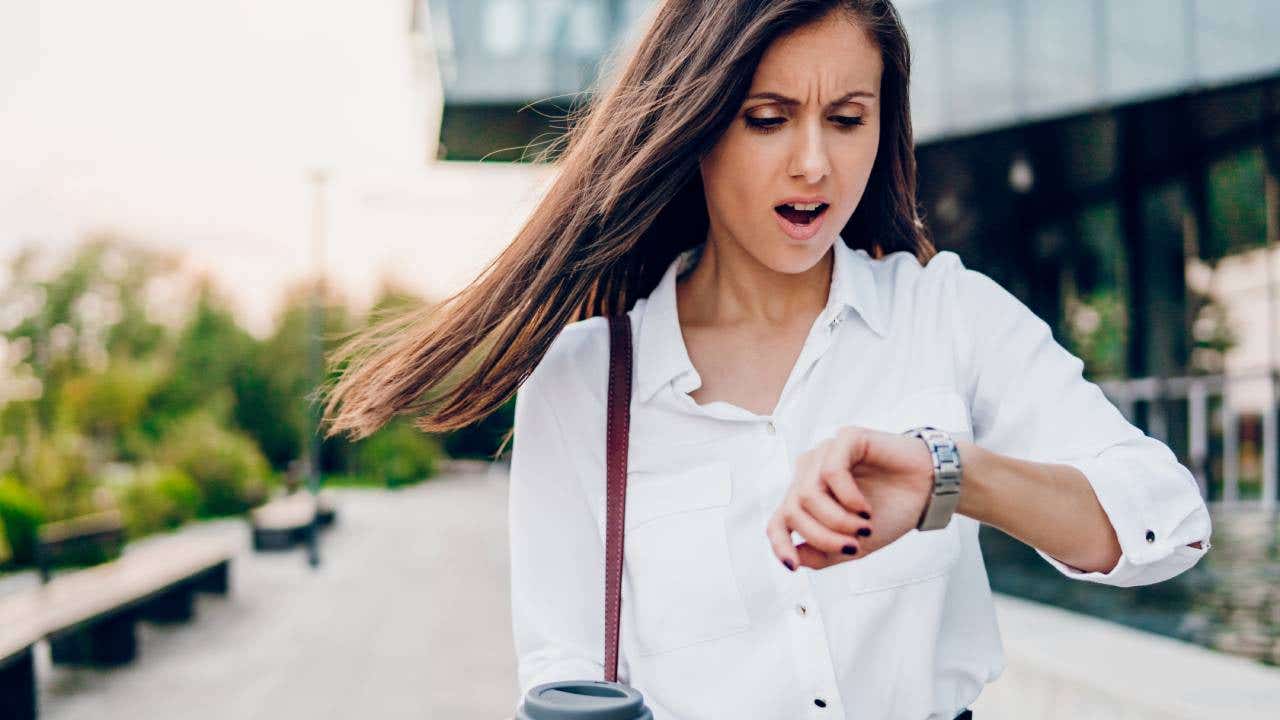 A woman who looks alarmed looks at her watch.