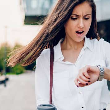 A woman who looks alarmed looks at her watch.