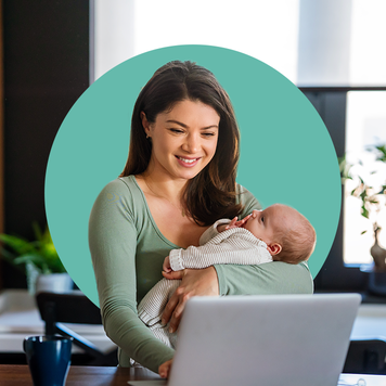 Woman workng and holding baby.