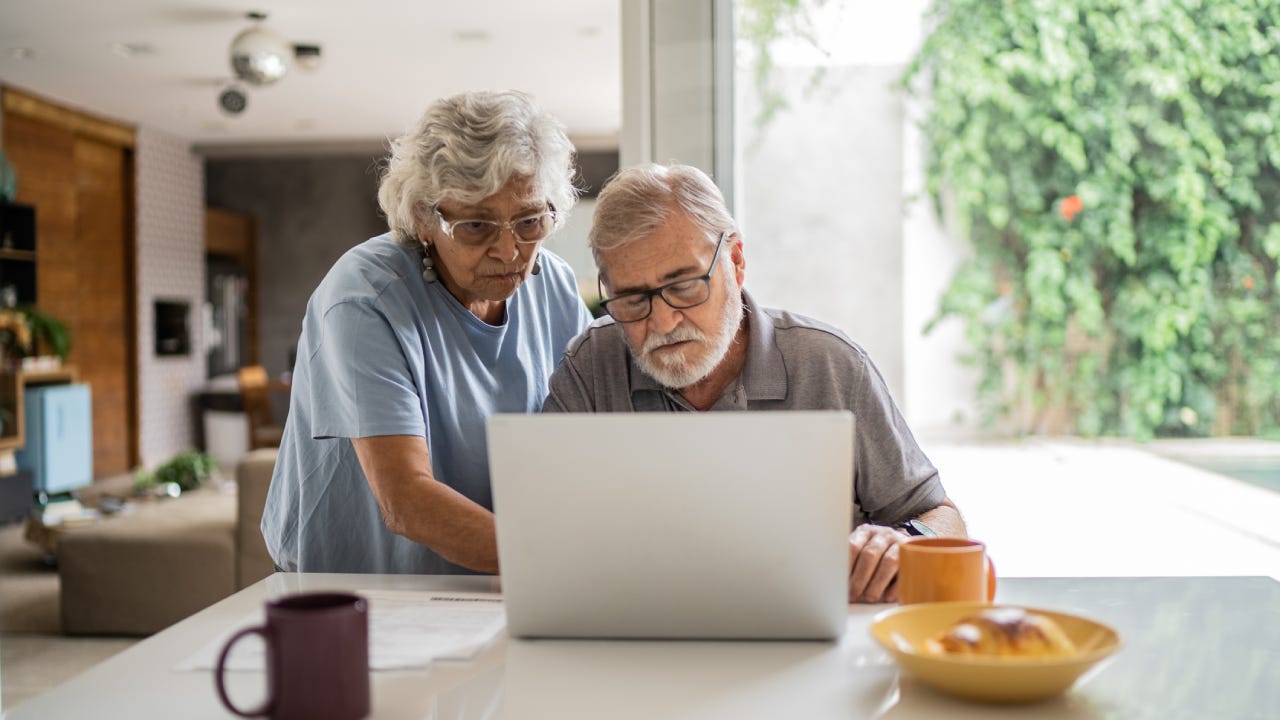 Senior couple talking about home finances and using the laptop at home