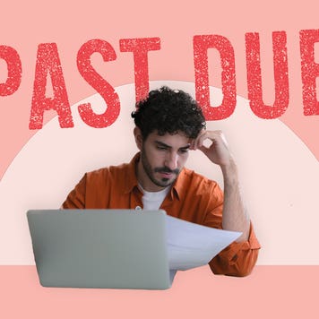 A man sitting in front of an open laptop computer looking down at some papers in his right hand. His left elbow is on the table and his head is leaning on his left hand.