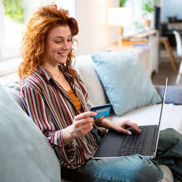 Young woman holding credit card and laptop