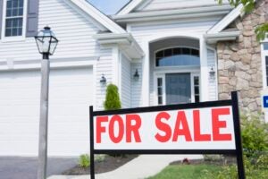 white and stone house exterior with for sale sign