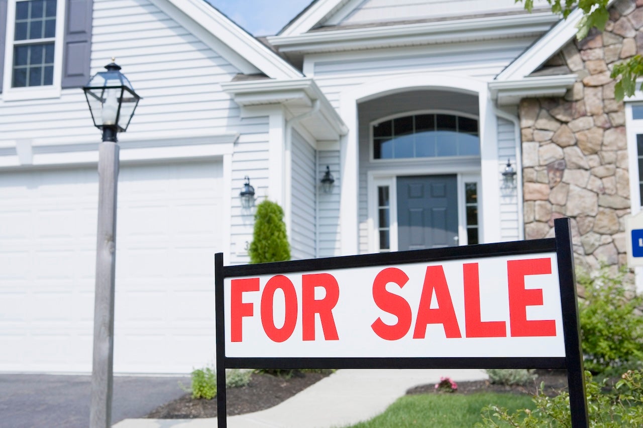 white and stone house exterior with for sale sign