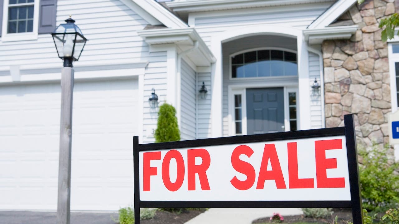 white and stone house exterior with for sale sign