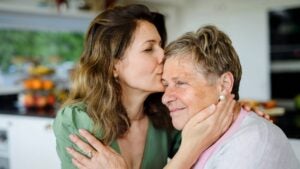A young woman kisses her grandmother on the cheek.