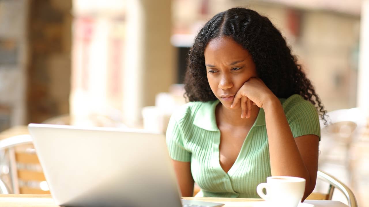 A serious woman studies her laptop.