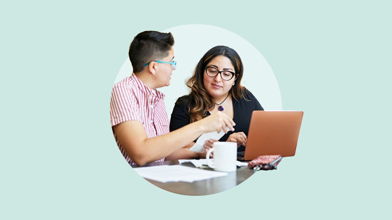 A couple reviewing a note and looking at a laptop.