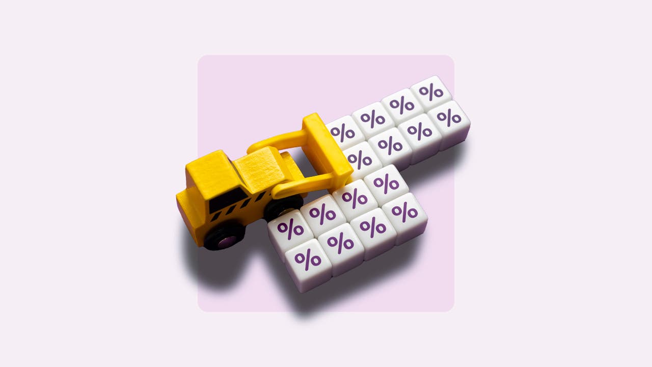 Toy backhoe pushing blocks with percent signs.