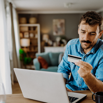 Young man using his credit card on the laptop