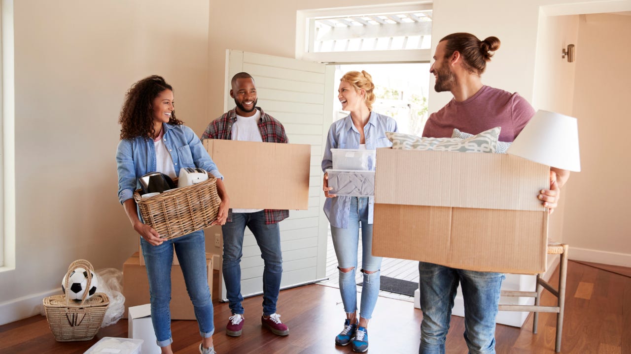 Friends carrying boxes into their new home