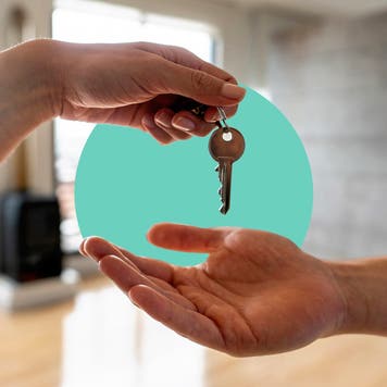 A hand holding a set of keys and giving it to another hand