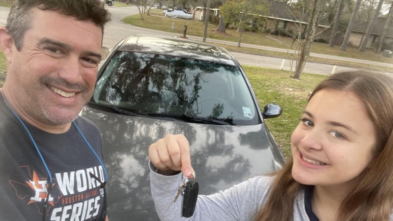 Father and daughter in front of car