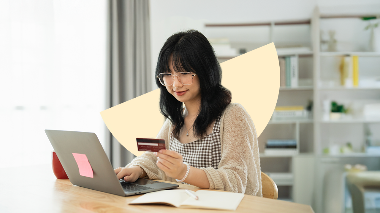 Woman at table holding credit card and typing on laptop