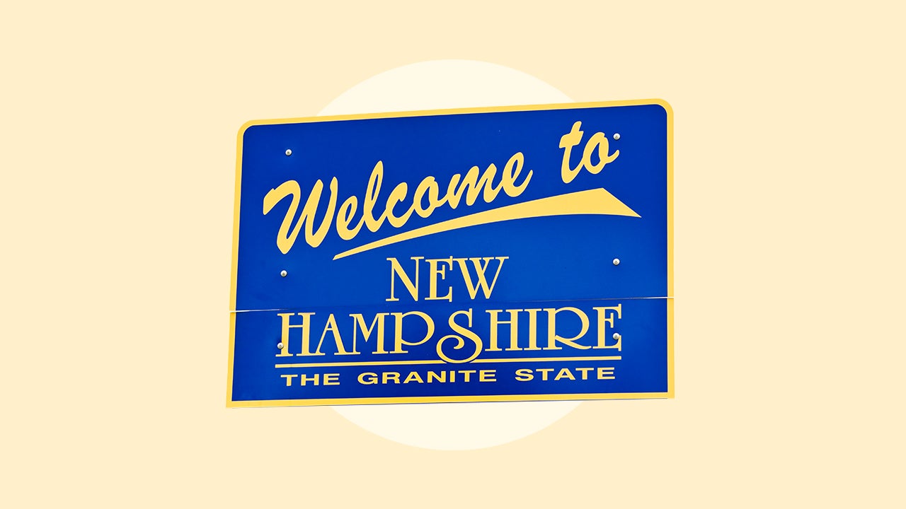 A blue sign with gold lettering saying "Welcome to New Hampshire The Granite State"