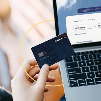 Person holding credit card at a laptop, booking a flight