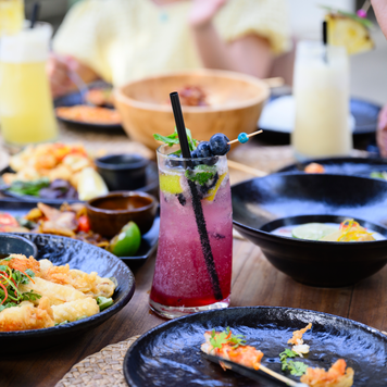 Focus on platters of seafood and refreshment as vacationers enjoy afternoon meal.