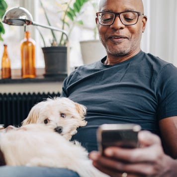Smiling man using smart phone while sitting with dog