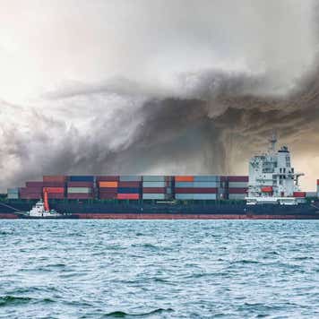 A container ship in choppy seas with storm clouds above.