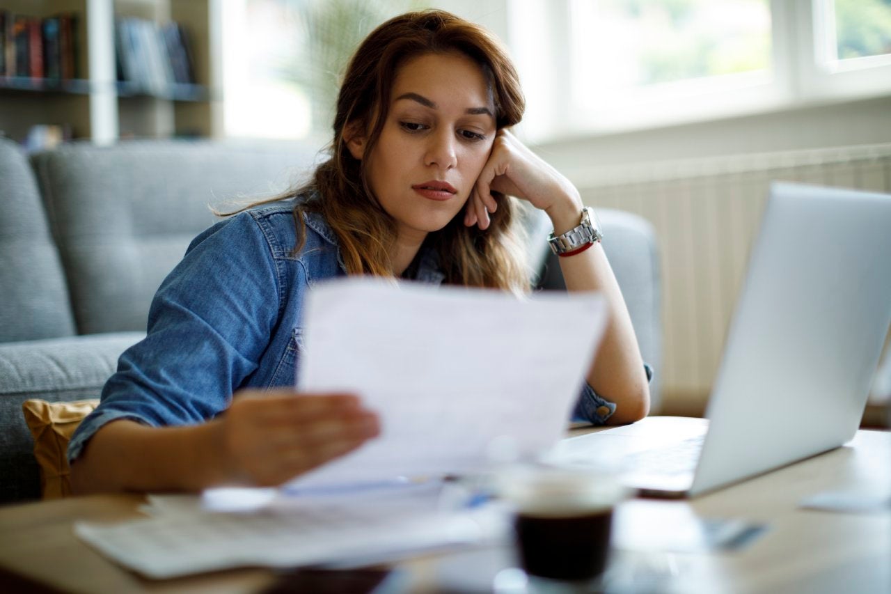 Worried woman about home finances while looking at some documents in front of her laptop