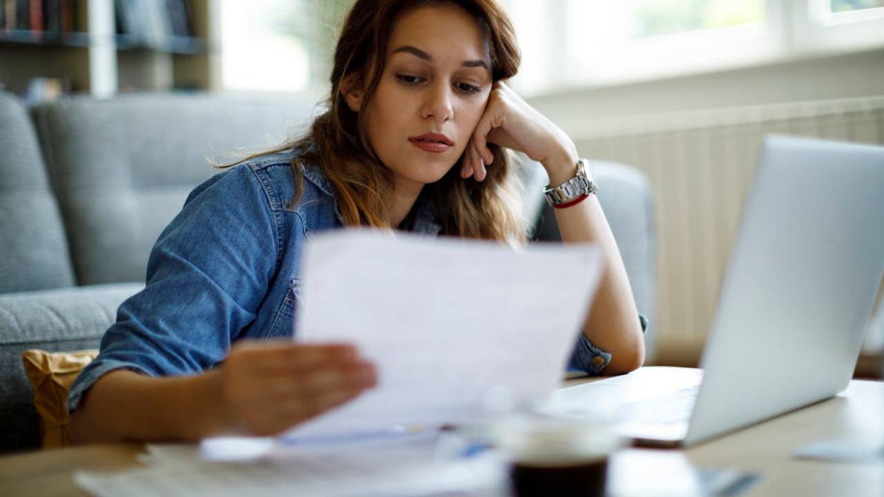 Worried woman about home finances while looking at some documents in front of her laptop
