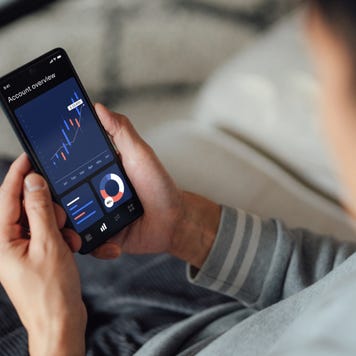 Over the shoulder view of young man checking financial data with mobile banking app